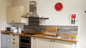 Una cucina con microonde, forno, lavello e piano di lavoro in legno.