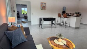 A modern living room with a sofa, a coffee table, and a foosball table. - Surf City Private 7 Suite Hotel with AC + hot water (Conchalio)