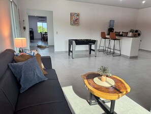 Un salon moderne avec un canapé, une table basse et un baby-foot.
