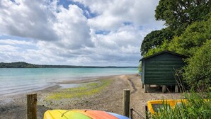 A beach with kayaks, a wooden hut, and a clear sky.