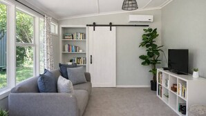A modern living room with a grey sofa, a bookshelf, a TV, and a sliding door.