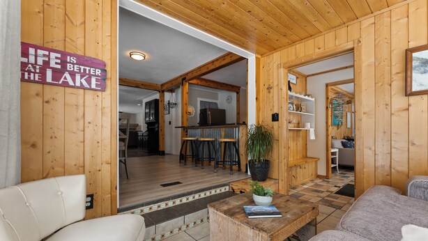 Un intérieur en bois avec un canapé, une table basse et un panneau sur lequel on peut lire : « La vie est plus belle au bord du lac. »