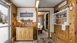 Un intérieur en bois comprenant un coin cuisine, une enseigne sur laquelle on peut lire « LAKEAHOLIC », et une vue sur l’extérieur.