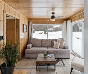 A wooden-paneled room with a sofa, a coffee table, and a potted plant.