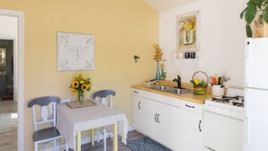 Una cocina con una mesa de comedor, sillas, un lavamanos, una estufa y un refrigerador.