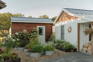A garden with various plants and a small wooden shed. - Snug Harbor Inn | Dunegrass Suite | ADA - Accessible Studio (Muskegon)