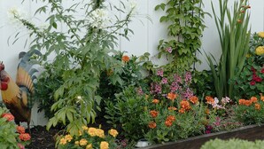 Un jardin agrémenté d’une décoration solaire en métal, ainsi que de diverses plantes et fleurs.