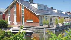 A modern house with a sloped roof, large windows, and a dock with a boat. - Dorregeest kalender 1 (Uitgeest)