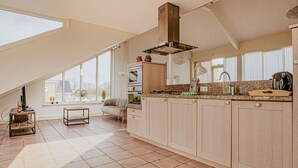 Una cucina con soffitto alto, ampie finestre e vista sull'esterno.
