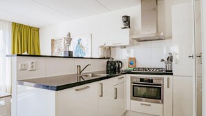 Ett modernt kök med vita skåp, en svart bänkskiva, en inbyggd ugn och en kaffebryggare.