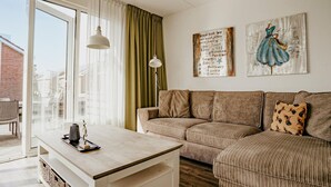 Ett mysigt vardagsrum med en soffa, ett soffbord och utsikt genom ett stort fönster.