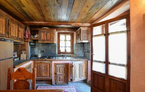 A rustic kitchen with wooden cabinets, a stone backsplash, and a window with a view. - Amazing apartment in Cogne (Cogne)