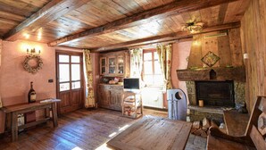 Een rustiek houten interieur met houten vloeren, een open haard, een eettafel en een televisie.