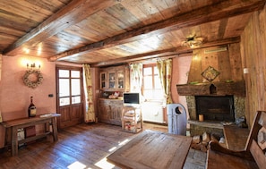 A rustic cabin interior with wooden floors, a fireplace, a dining table, and a television. - Amazing apartment in Cogne (Cogne)