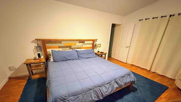 Une chambre à coucher avec un lit, une tête de lit en bois, des tables de chevet et un tapis bleu.