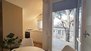 A modern kitchen with a gas stove, oven, and a view of a balcony with a tree and railing. - 1 bedroom nice apartment in Cattolica (Cattolica)