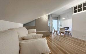 A modern loft bedroom with a built-in sofa, a dining area with a table and chairs, and a large window providing natural light. - 1 bedroom nice apartment in Cattolica (Cattolica)