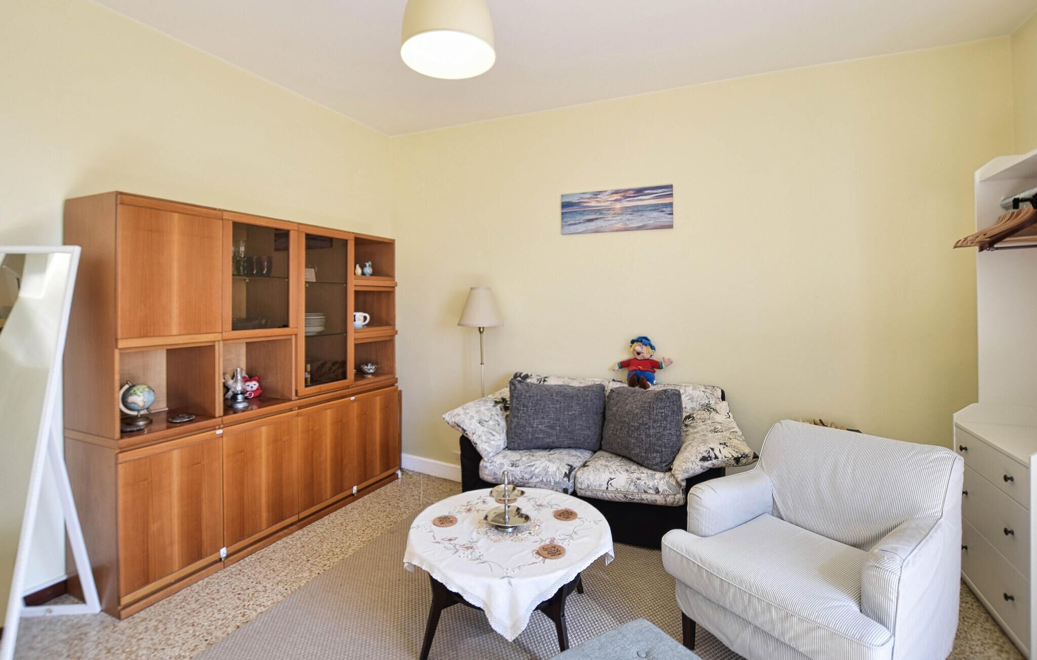 A living room with a sofa, a small table, a wooden cabinet, and a lamp.
