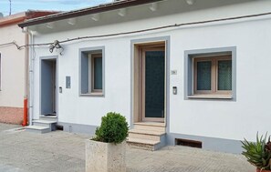 Ein modernes Gebäude mit drei Fenstern und Türen, ein kleiner Gartenbereich mit einem Blumentopf und die Hausnummer 134, deutlich sichtbar an der Wand.
