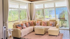 A modern living room with a sectional sofa, a glass coffee table, and a chandelier. - Cozy Villa Mountain View Cold Weather in Marilog Perfect for Relaxing getaways (Arakan)