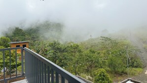A view from a balcony overlooking a lush green landscape with a wooden building in the foreground. - Cozy Villa Mountain View Cold Weather in Marilog Perfect for Relaxing getaways (Arakan)