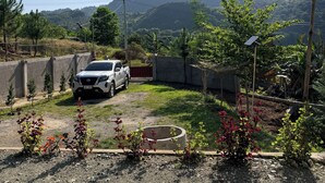 A white car parked in a gravel area with a view of a mountainous landscape. - Cozy Villa Mountain View Cold Weather in Marilog Perfect for Relaxing getaways (Arakan)
