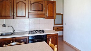 A kitchen with wooden cabinets, a sink, a stove, and a countertop. - 2 bedroom lovely apartment in Ricadi (Ricadi)