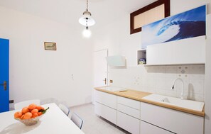 A modern kitchen with a white countertop, a sink, and a hanging light fixture. - 1 bedroom stunning apartment in Tropea (Tropea)