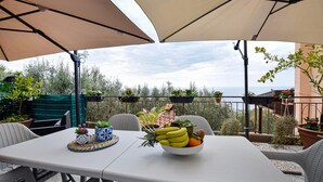 Una mesa con un frutero y plantas en macetas, mesas al aire libre y vista al mar.