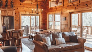 Ein Holzblockhaus-Interieur mit einer Couch, einem Esstisch, Stühlen und einem Kühlschrank.