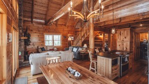 Ein Holzblockhaus-Interieur mit einem Holzesstisch, einer Couch und einer Küchenzeile.
