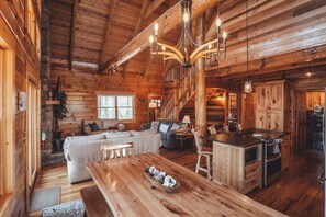 Ein Holzblockhaus-Interieur mit einem Holzesstisch, einer Couch und einer Küchenzeile.