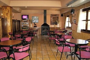 A restaurant with multiple tables and chairs, a fireplace, a television, and artwork on the walls. - Hotel Riopar Spa (Riopar)
