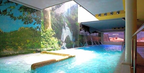 An indoor swimming pool with a waterfall feature and a mural of a forest scene. - Hotel Riopar Spa (Riopar)