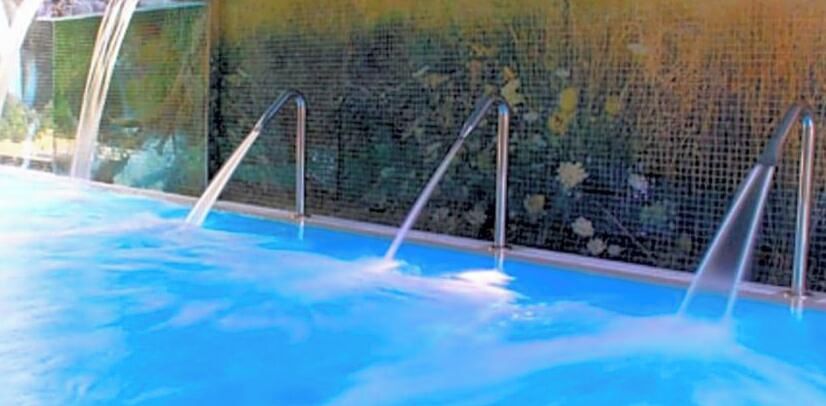 Una piscina con escaleras de metal y una pared de azulejos.