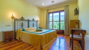 A bedroom with a bed, a nightstand, a desk, a chair, a window with a view, and a radiator. - Hotel Riopar Spa (Riopar)