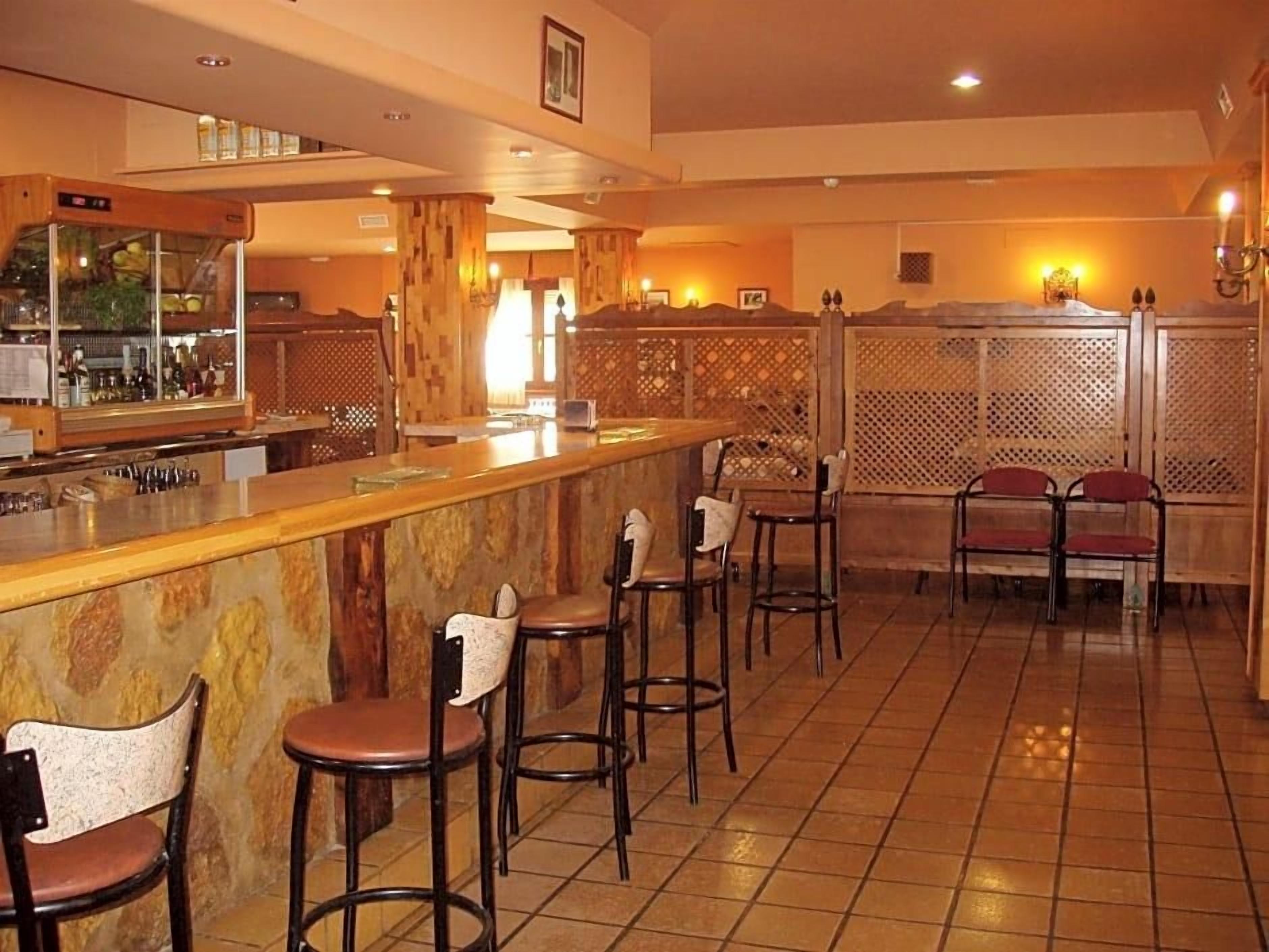 Una zona de bar con taburetes, mostrador y separador con diseño de celosía.