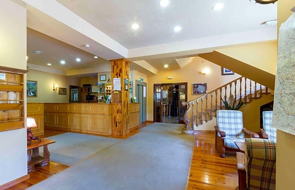 Un vestíbulo amplio con suelo de madera, un mostrador de recepción, una escalera y una zona de estar con sillas a cuadros.
