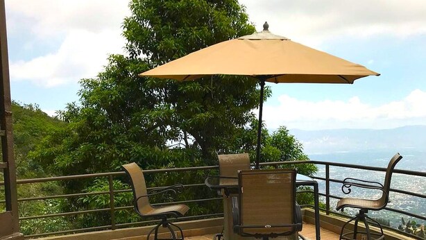 Eine Terrassengaststätte mit Tisch und Stühlen, einem großen Sonnenschirm und Blick auf das Meer.