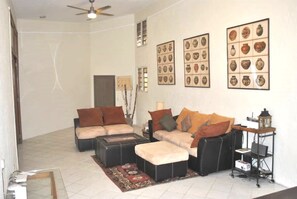 Sala de estar com sofá, mesa de centro e tapete. Quadros emoldurados na parede.