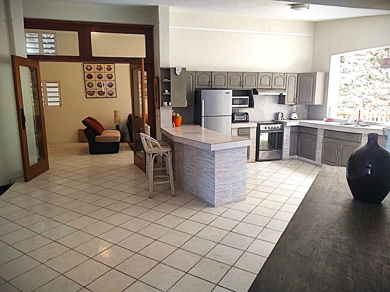 Una cucina moderna con isola centrale, elettrodomestici integrati e zona pranzo con sedia e tavolo.