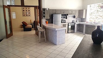 Una cucina moderna con isola centrale, elettrodomestici integrati e zona pranzo con sedia e tavolo.