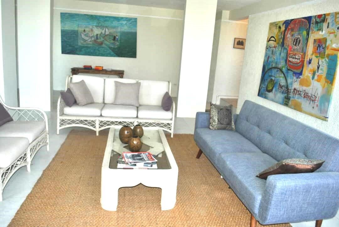 Un salon avec un canapé blanc, un canapé bleu et une table basse agrémentée d’objets décoratifs.
