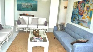 Ein Wohnzimmer mit einem weißen Sofa, einem blauen Sofa und einem Couchtisch mit Dekoration.