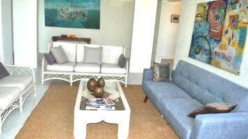 Un salon avec un canapé blanc, un canapé bleu et une table basse agrémentée d’objets décoratifs.
