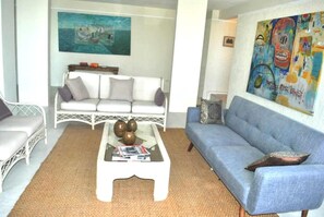 Un salon avec un canapé blanc, un canapé bleu et une table basse agrémentée d’objets décoratifs.