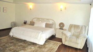 Ein Schlafzimmer mit Bett, Nachttischen, einem Sessel und Wandleuchten.