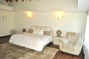 Une chambre à coucher comprenant un lit, des tables de chevet, une chaise et des lampes fixées au mur.