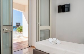 A hotel room with a bed, a TV, and a view of the sea. - ISA Marina Riva Le Nuove Dune (Porto Cesareo)