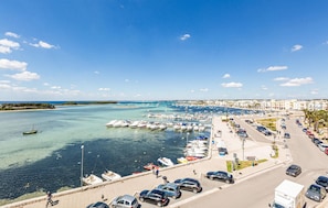 Ein Küstenhafen mit Booten, einem Parkplatz und einer Straße, die zum Strand führt.